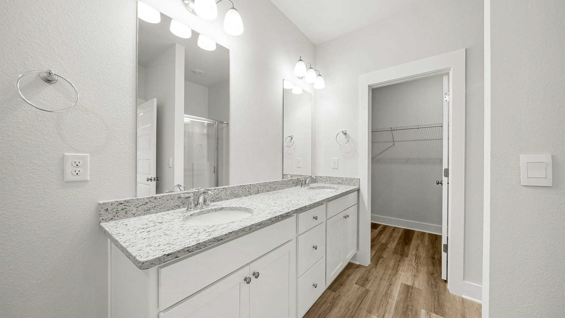 Primary bathroom with double vanity granite countertops and white cabinets.