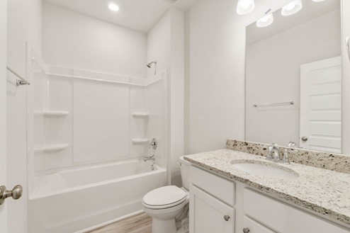 Bathroom with granite countertops and white cabinets and shower.