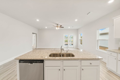 Main kitchen island with EVP flooring and granite countertops and stainless-steel appliances.