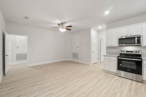 Second kitchen with EVP flooring and granite countertops and stainless-steel appliances.