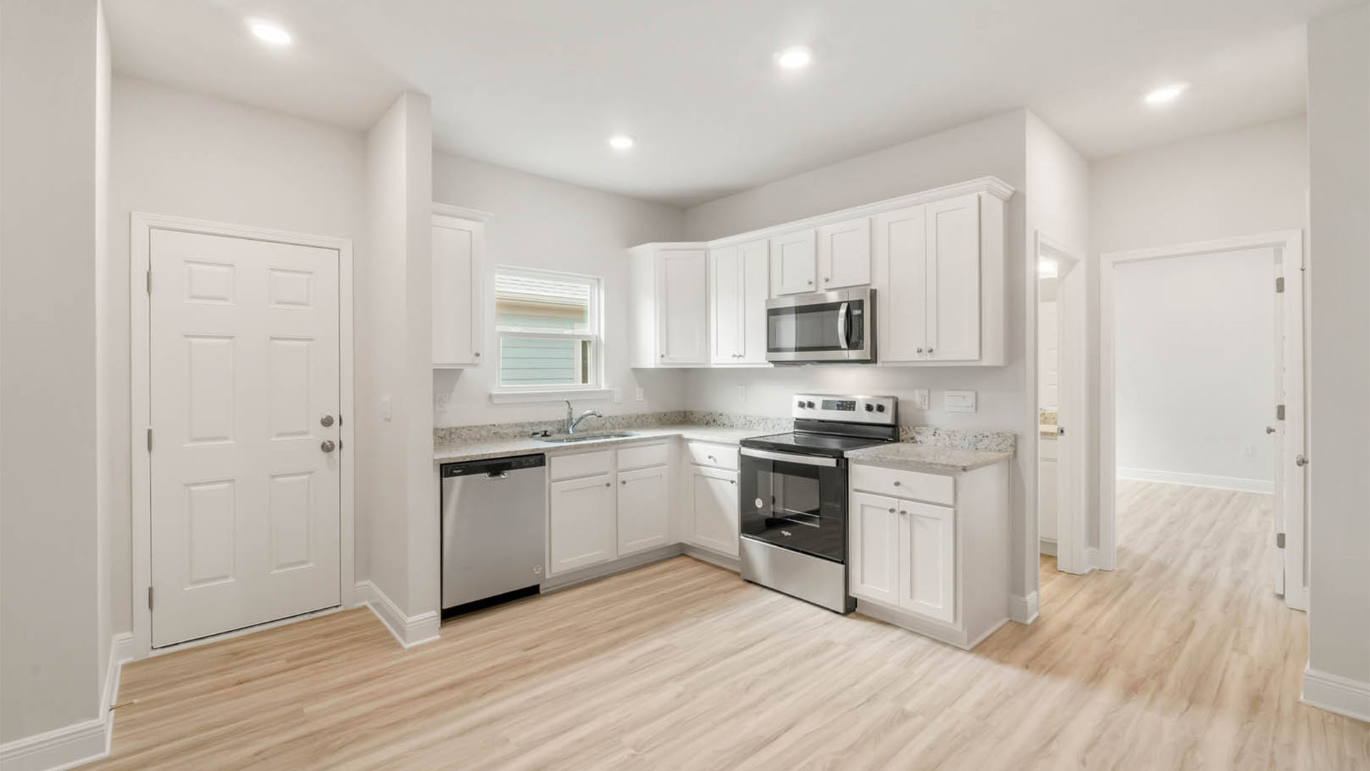 Second kitchen with EVP flooring and granite countertops and stainless-steel appliances.