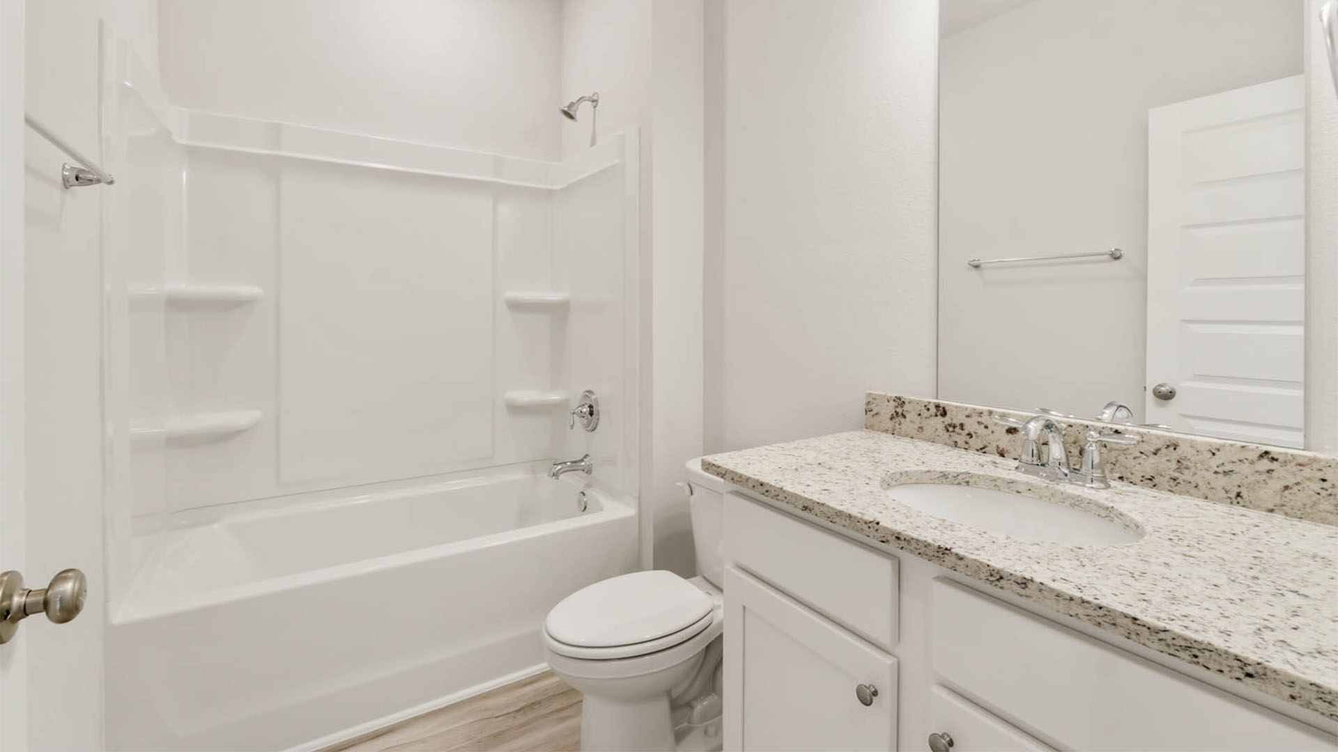 Bathroom with granite countertops and white cabinets and shower.
