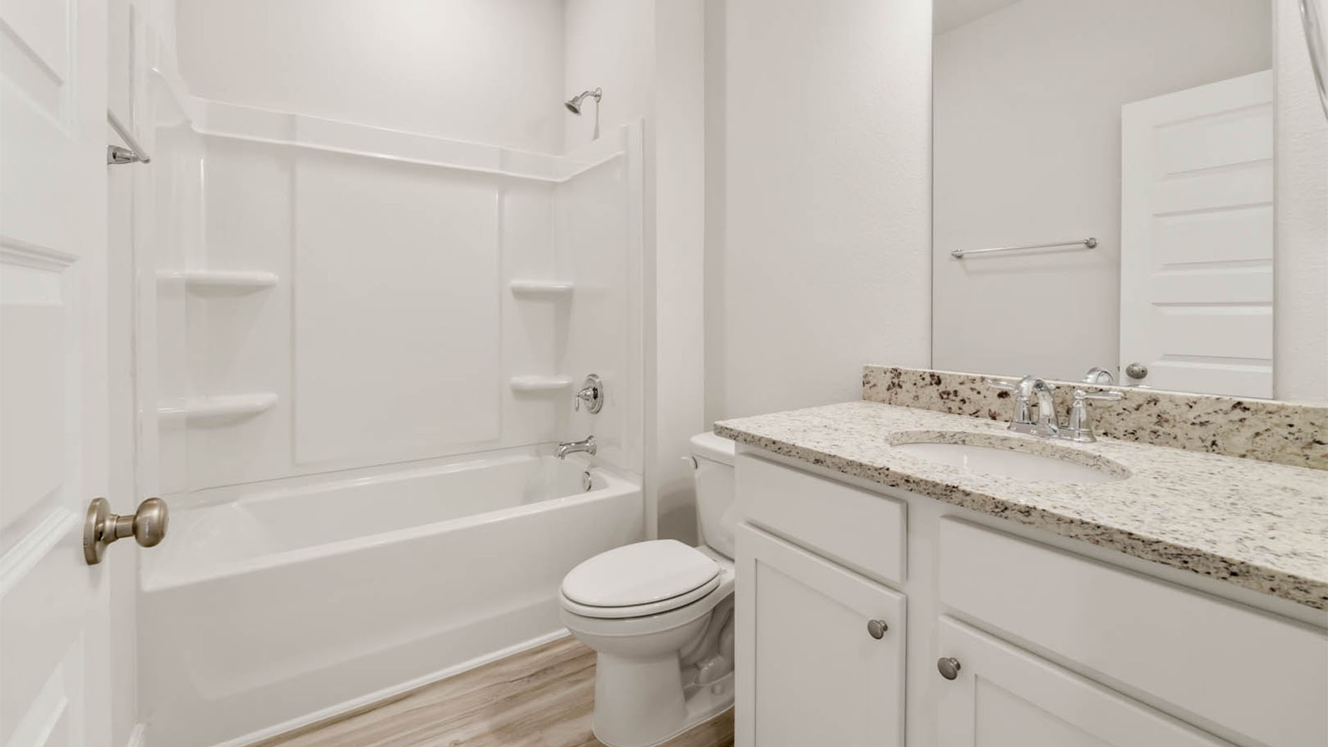 Bathroom with granite countertops and white cabinets and shower.