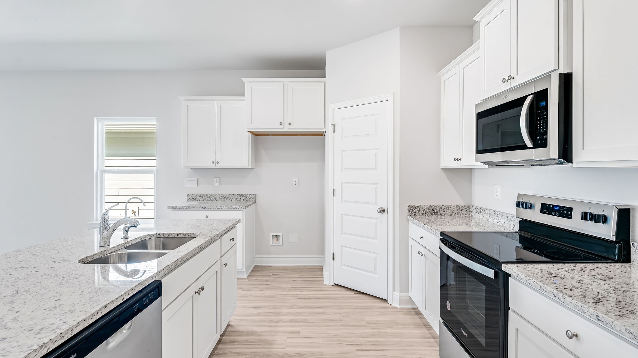 Open kitchen with EVP flooring and granite countertops and stainless-steel appliances and pantry.
