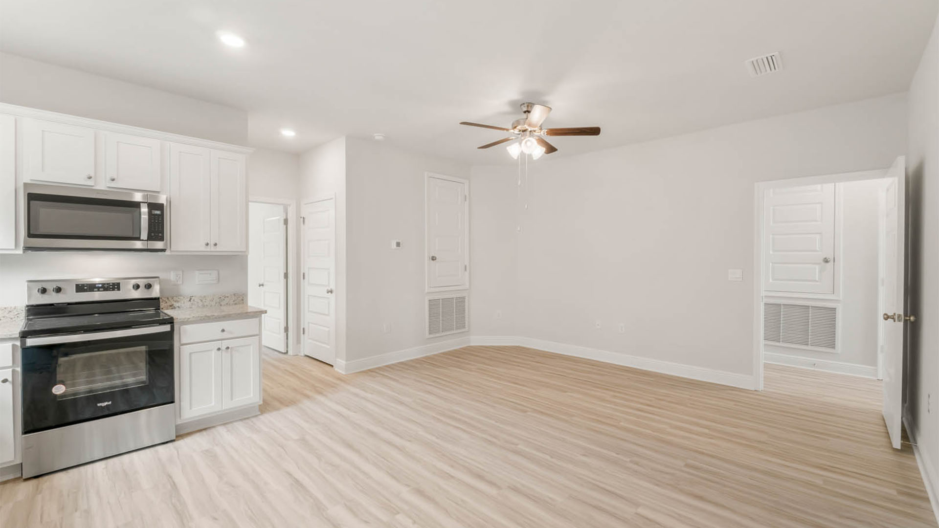 Second kitchen with EVP flooring and granite countertops and stainless-steel appliances.