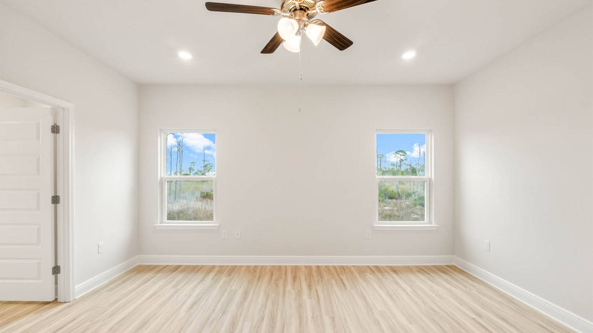 Primary bedroom with EVP flooring and ceiling fan and windows.