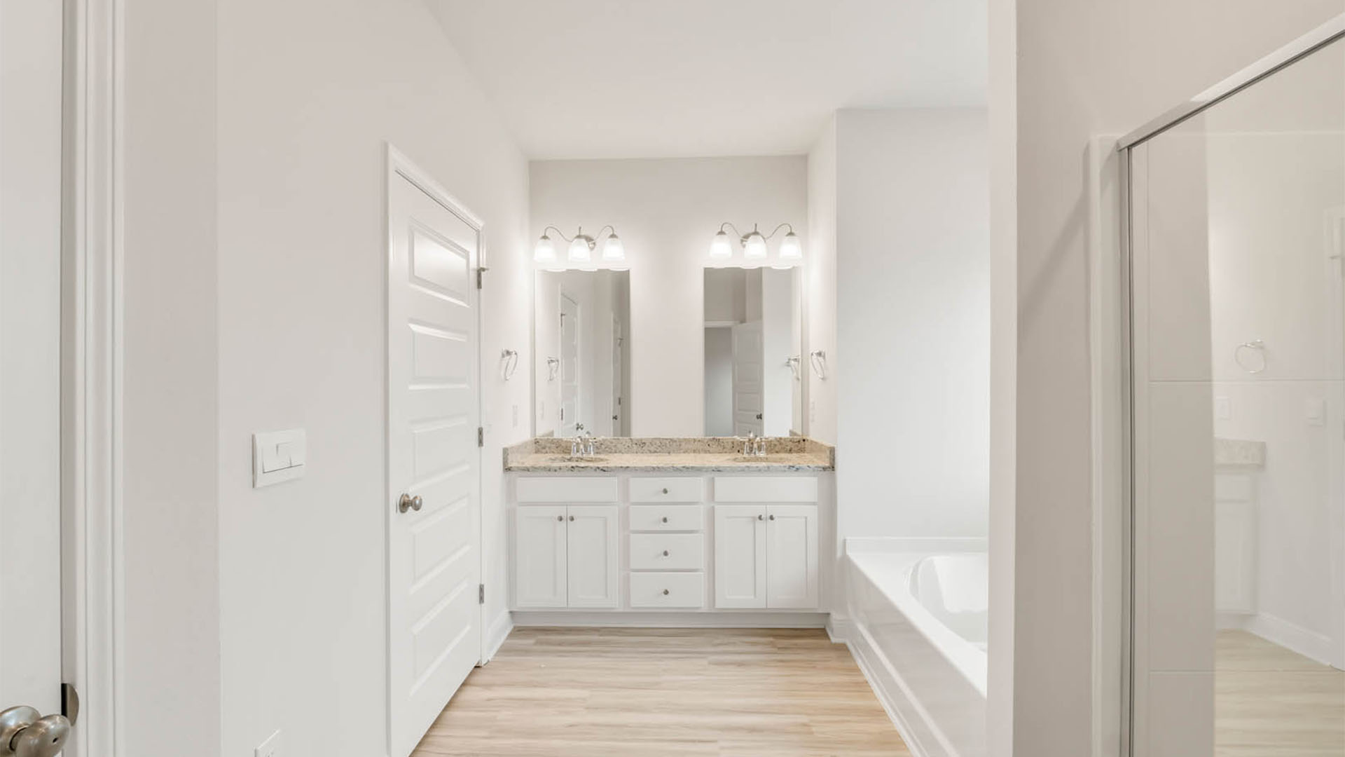 Primary bathroom with double vanity and granite countertops.