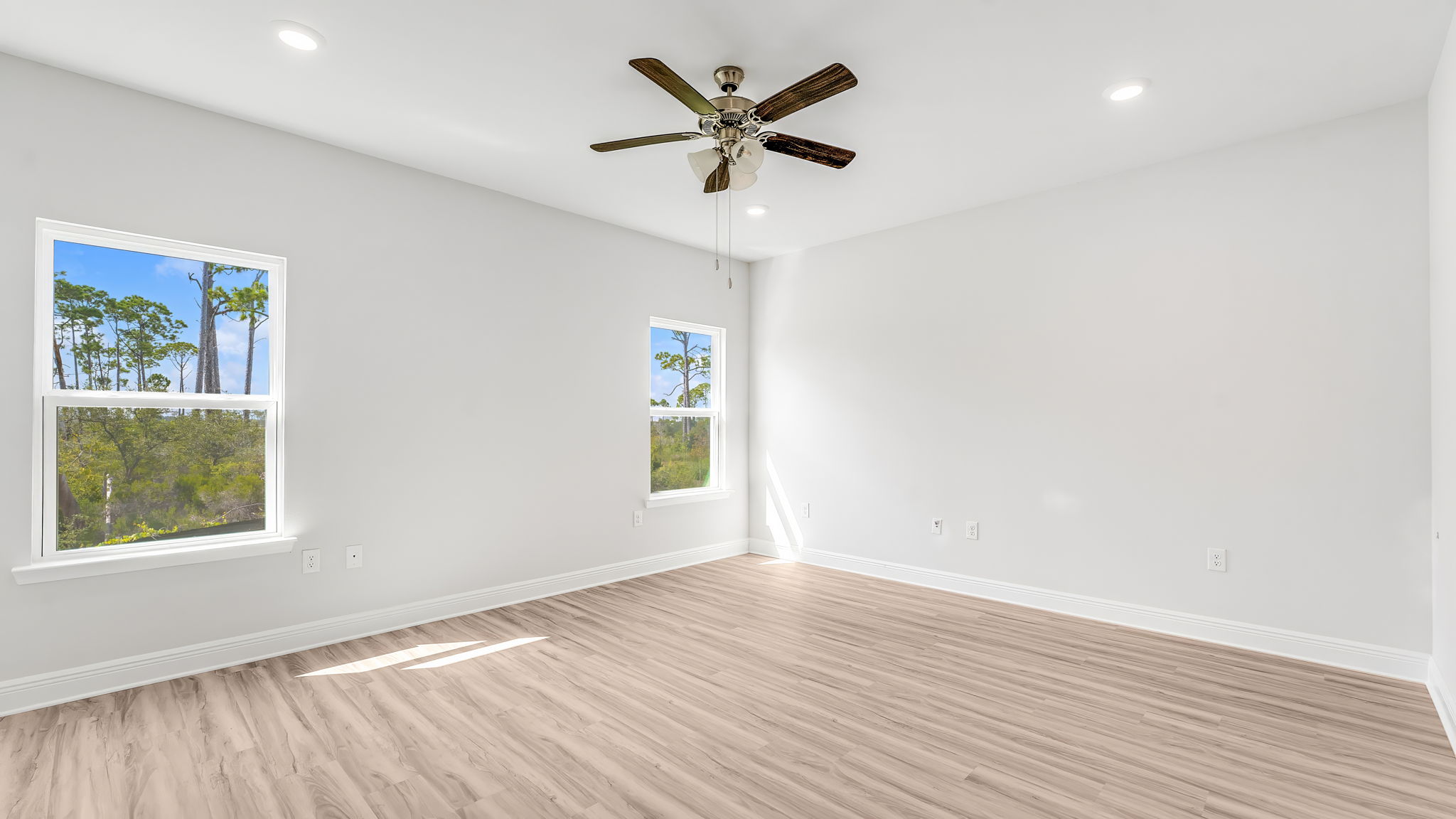 Primary bedroom with EVP flooring and ceiling fan and windows.