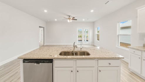 Main kitchen island with EVP flooring and granite countertops and stainless-steel appliances.