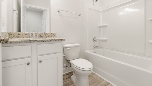 Bathroom with granite countertops and white cabinets and shower.