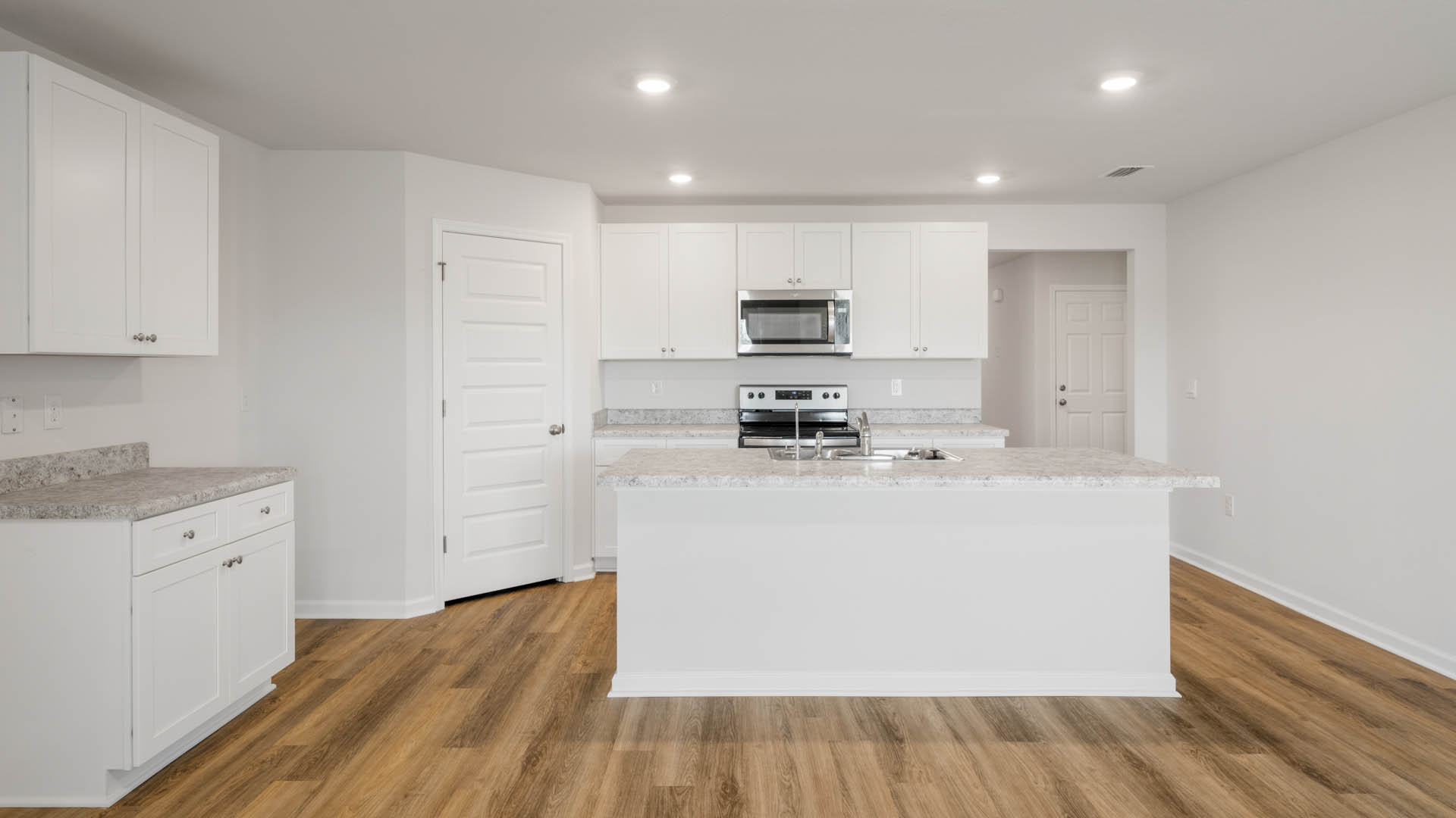 Kitchen Island with white cabinets and stainless-steel appliances and laminate countertops.