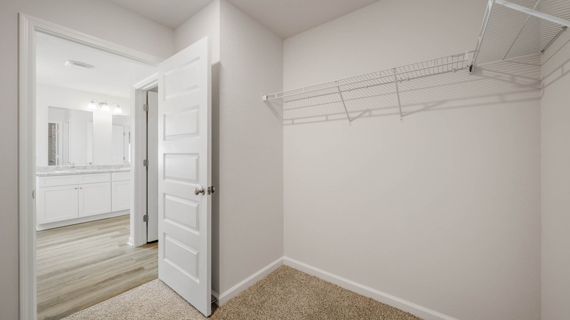 Walk-in closet with ventilated shelving and bathroom entrance.