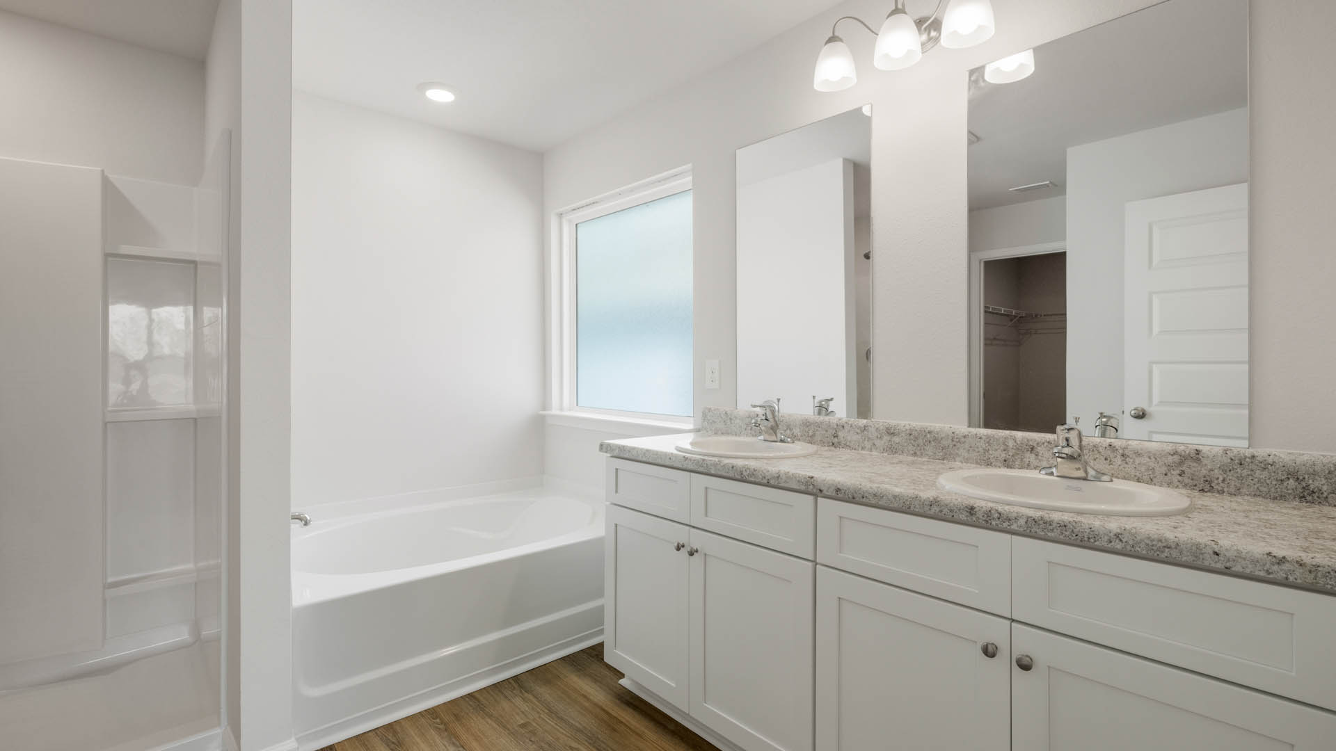 Primary bathroom with laminate countertops and double vanity and tub.