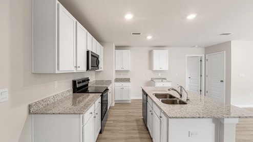 Kitchen island with granite countertops and stainless-steel appliances and white cabinets.