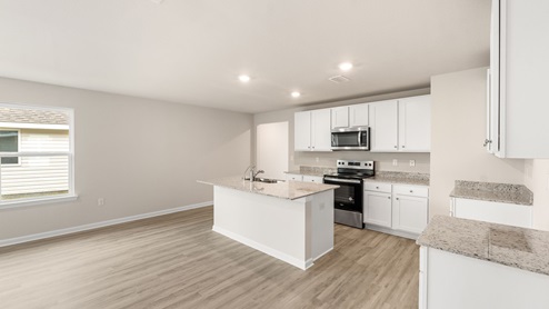 Kitchen island with granite countertops and stainless-steel appliances and white cabinets.