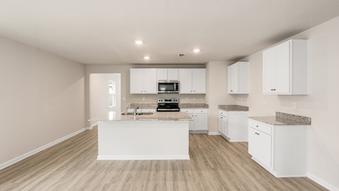 Kitchen island with granite countertops and stainless-steel appliances and white cabinets.