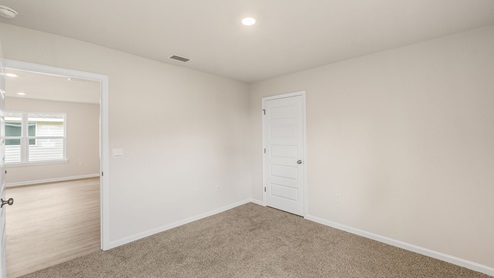 Bedroom with carpet floors and closet and living room entrance.