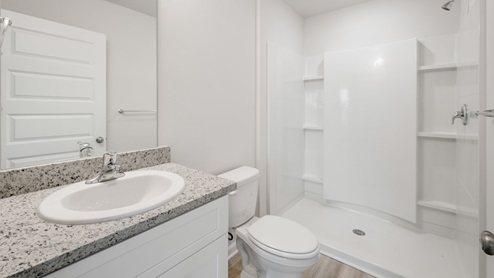 Primary bathroom with single-vanity granite countertop and shower and toilet.