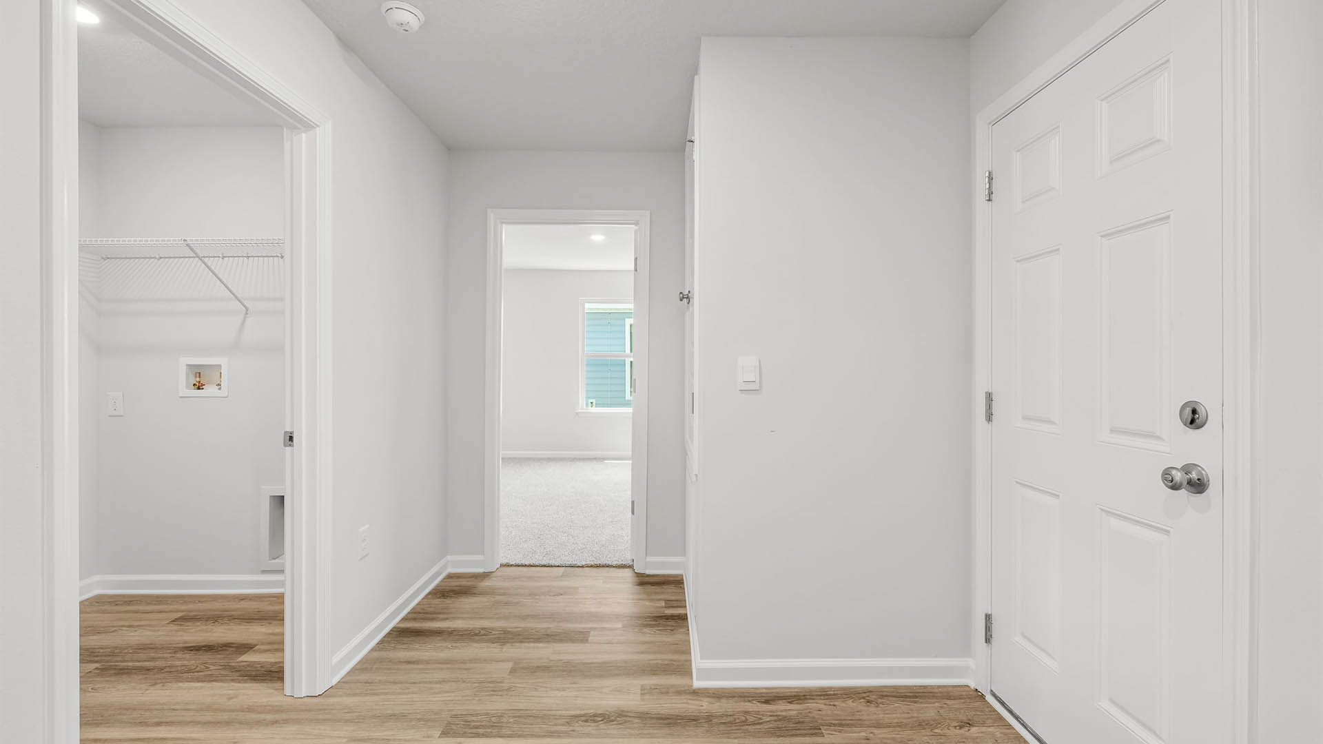 Hallway by garage entrance and bedroom and laundry room with EVP flooring.