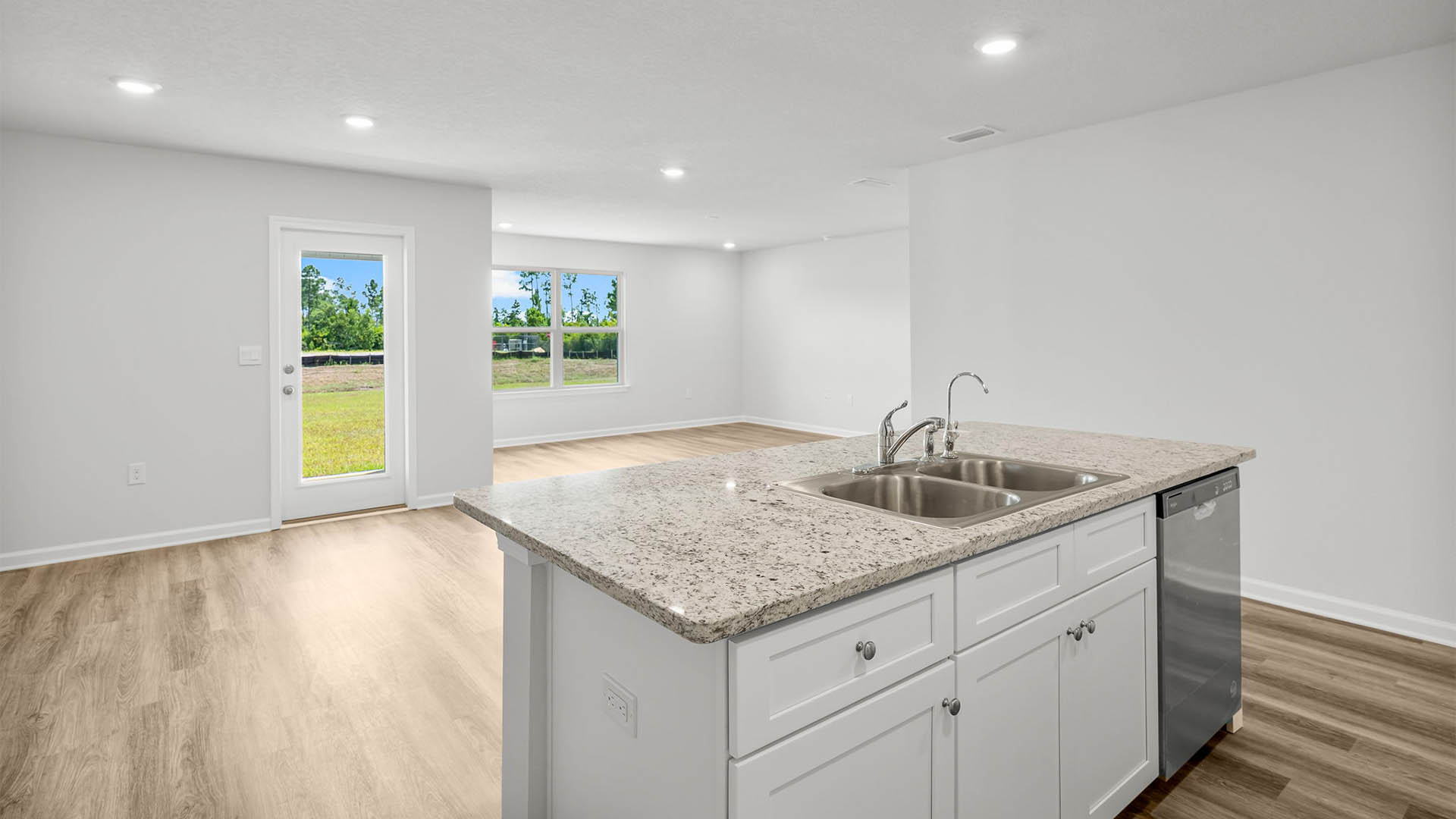 Kitchen island with undermount sink looking into dining area and back door and open living room.