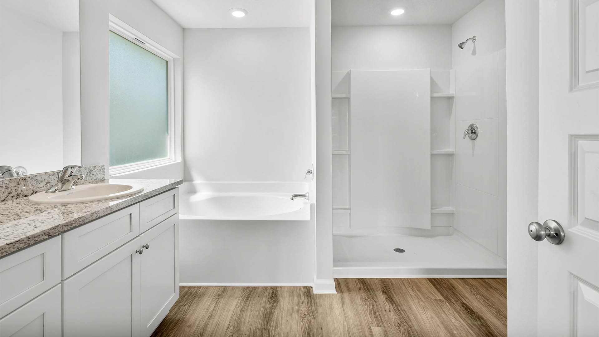 Primary bathroom with double vanity granite countertops and separate tub and shower and EVP flooring.