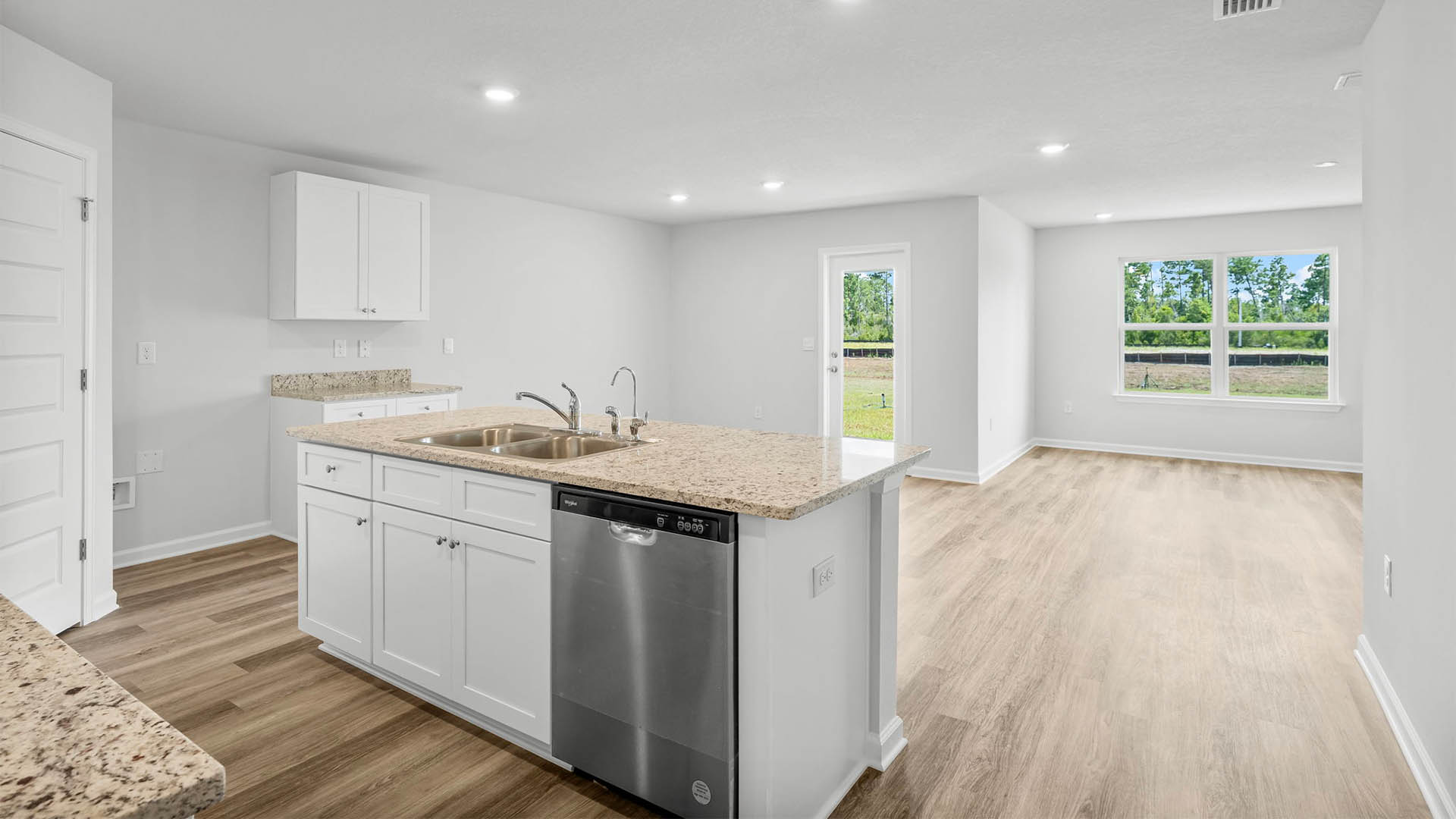 Kitchen island with white cabinets and stainless-steel appliances and granite countertops.