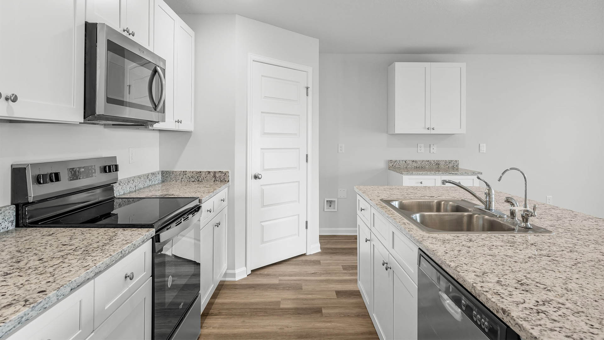 Kitchen with island and white cabinets and stainless-steel appliances and granite countertops and pantry.