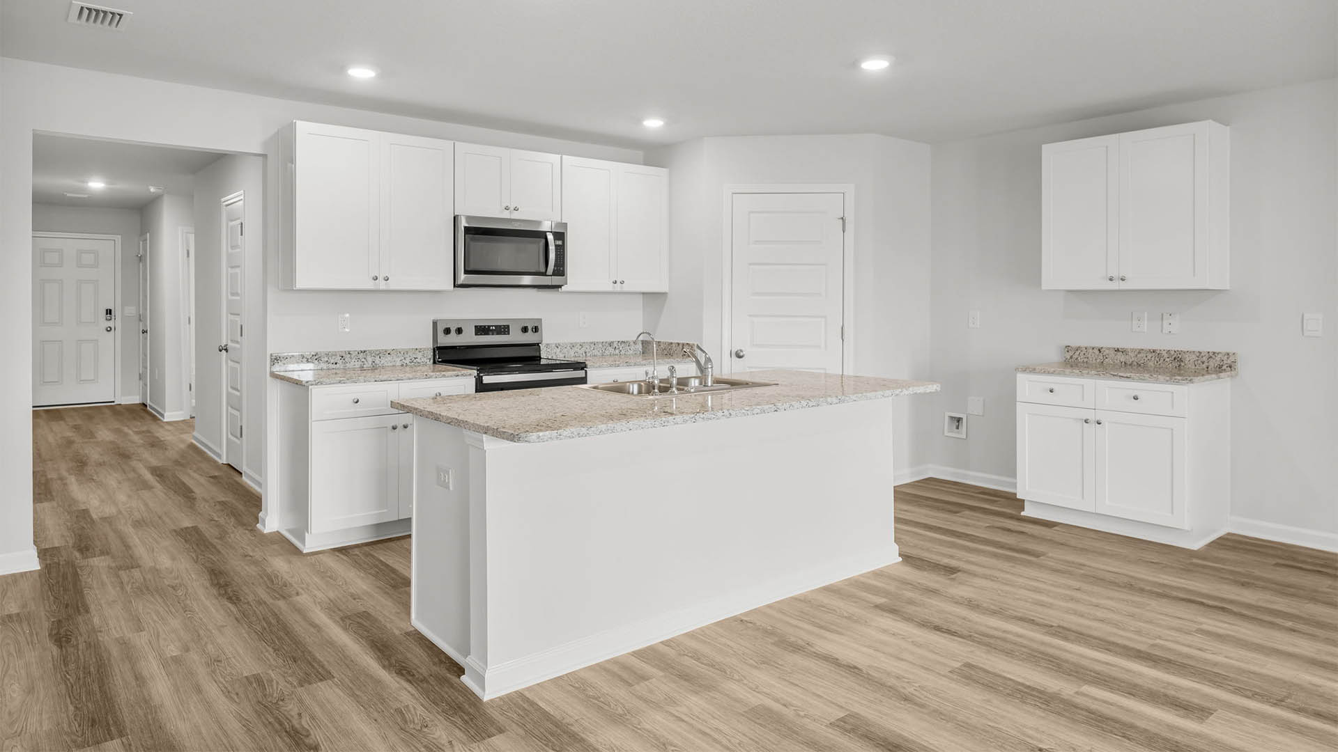 Kitchen with island and white cabinets and stainless-steel appliances and granite countertops and pantry.