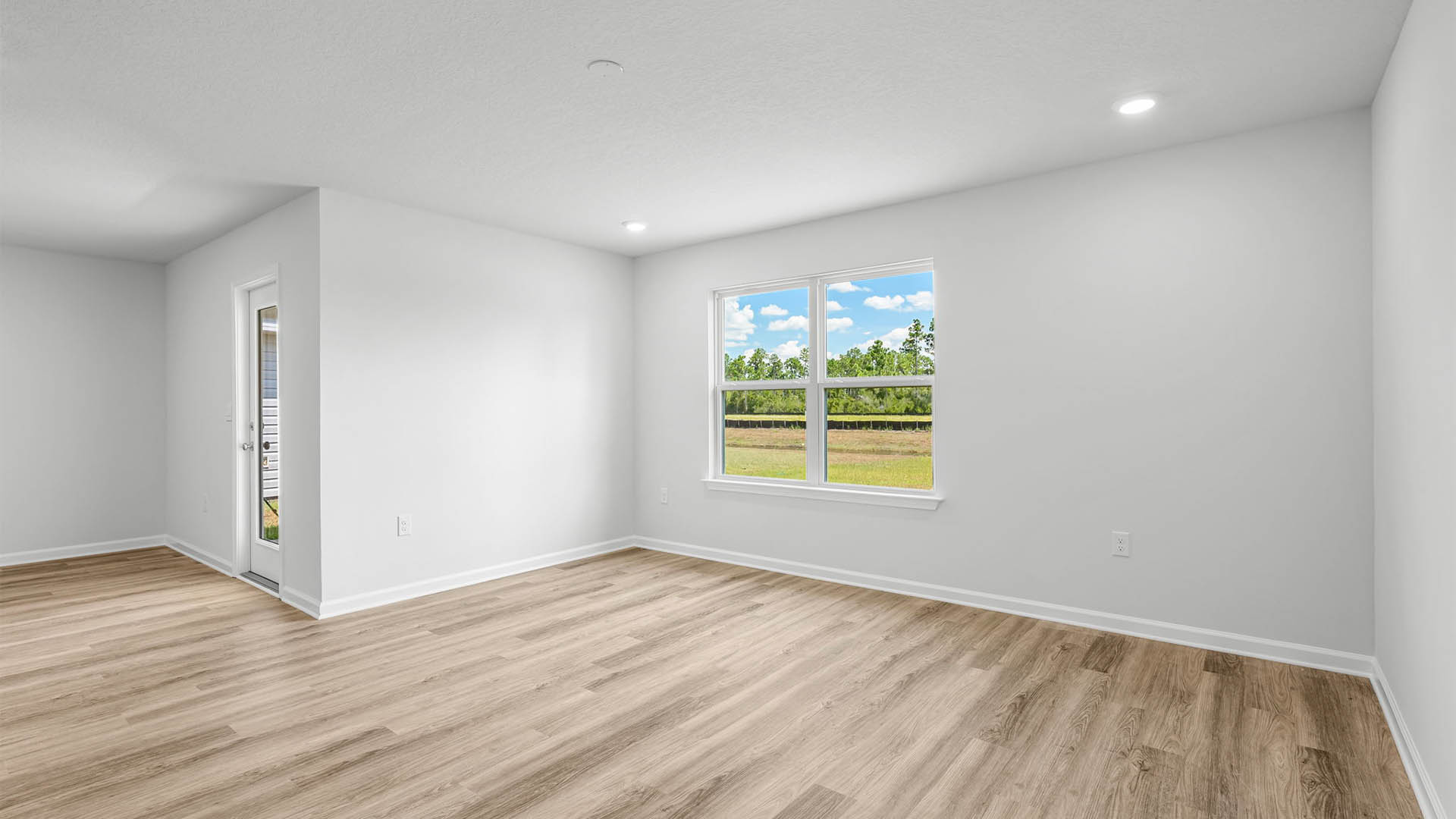 Open living room and dining area with EVP flooring and two windows and backdoor.