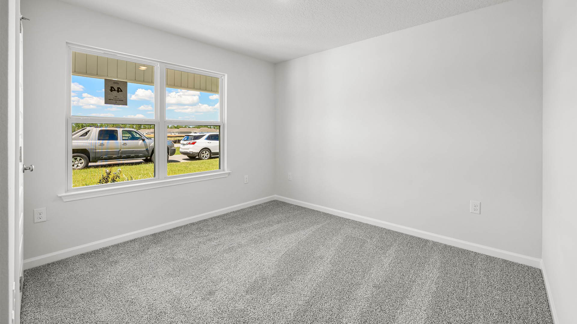 Bedroom with carpet flooring and two windows.
