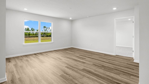 Open living room with EVP flooring and two windows next to primary bedroom entrance.