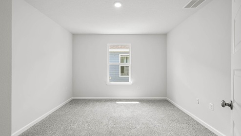 Bedroom with carpet flooring and window.
