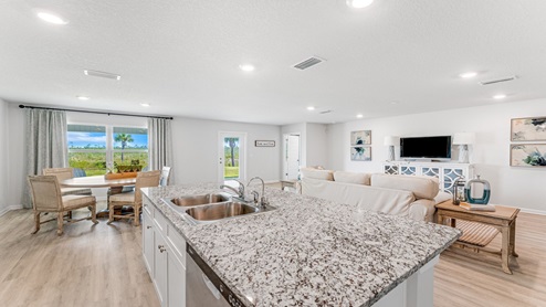 Kitchen island with granite countertops and dining area and open living room.