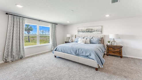 Primary bedroom with carpet floors and double window.