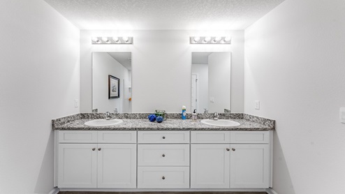 Primary bathroom double vanity granite countertops and white cabinets.