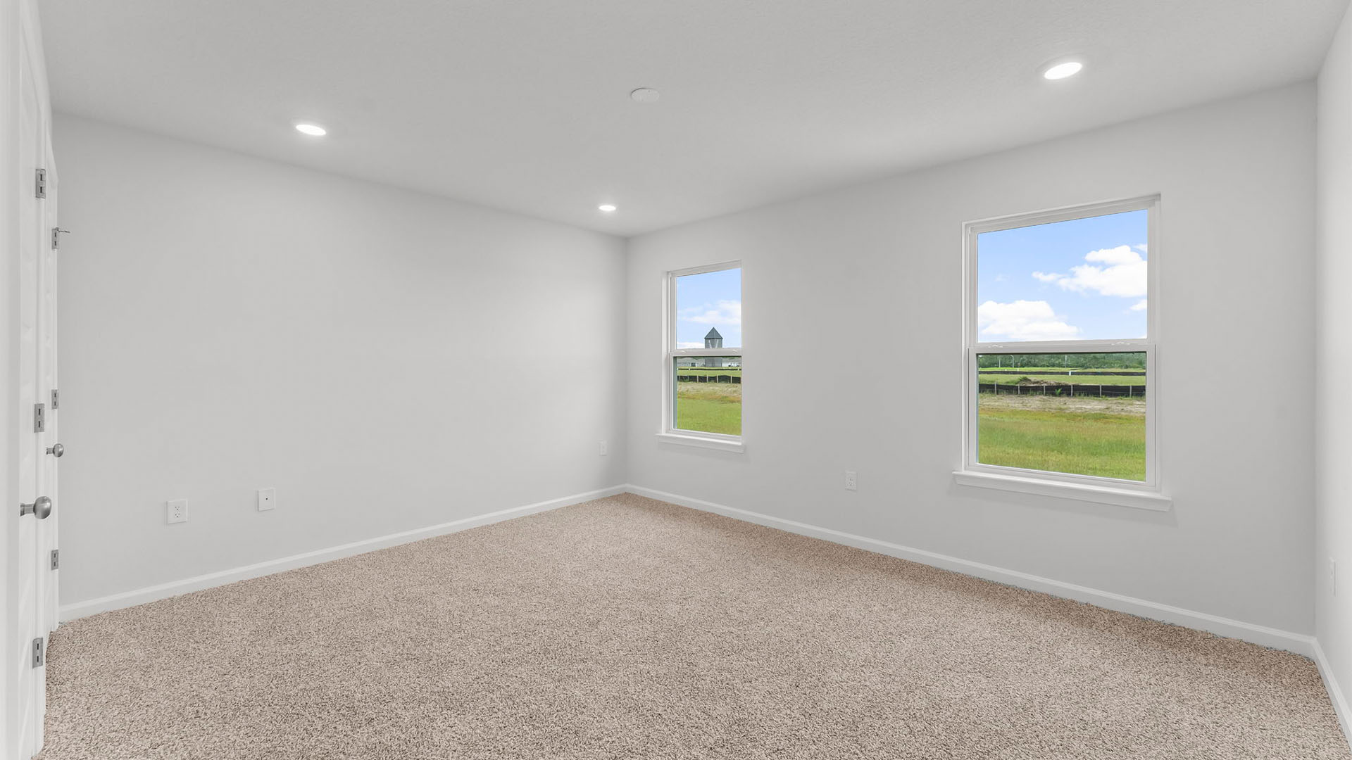 Primary bedroom with two windows and carpet floors.