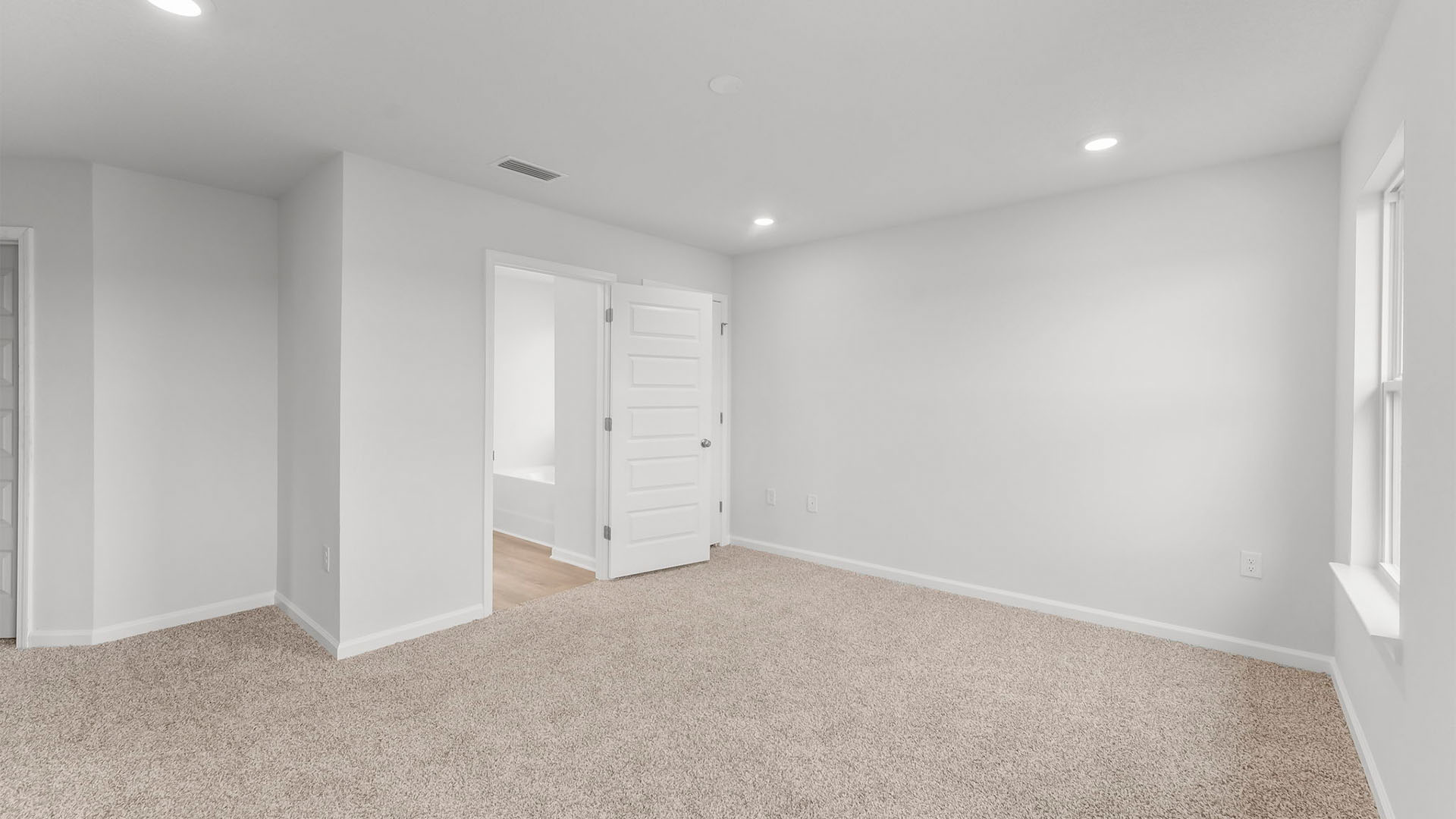 Primary bedroom with closet and bathroom entrance and carpet floors.