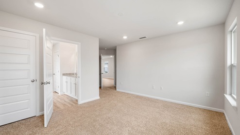 Primary bedroom with closet and bathroom entrance and carpet floors.