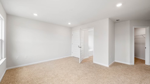 Primary bedroom with closet and bathroom entrance and carpet floors.