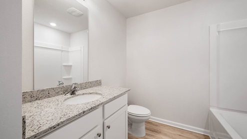 Bathroom with single vanity granite countertop and toilet and shower tub combo.