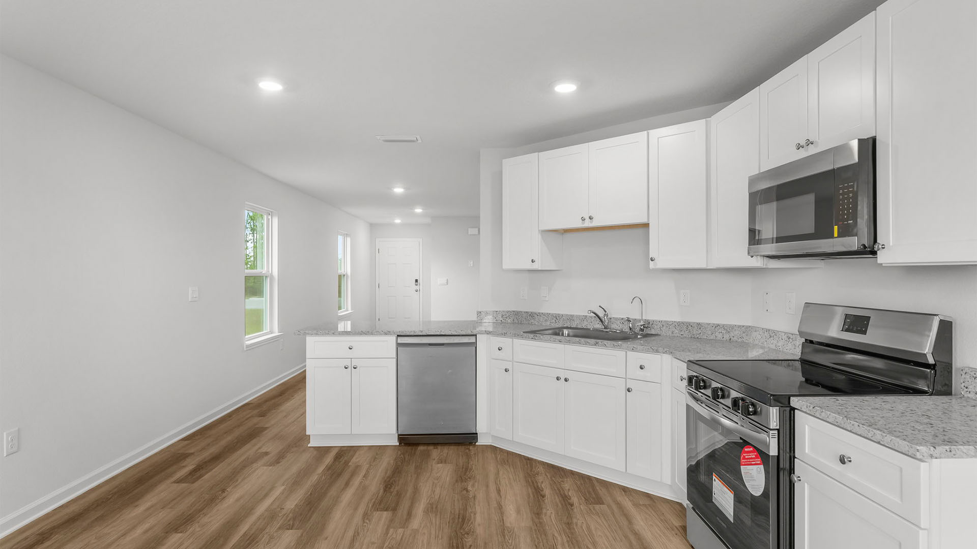Kitchen with EVP flooring and granite countertops and white cabinets and stainless-steel appliances.