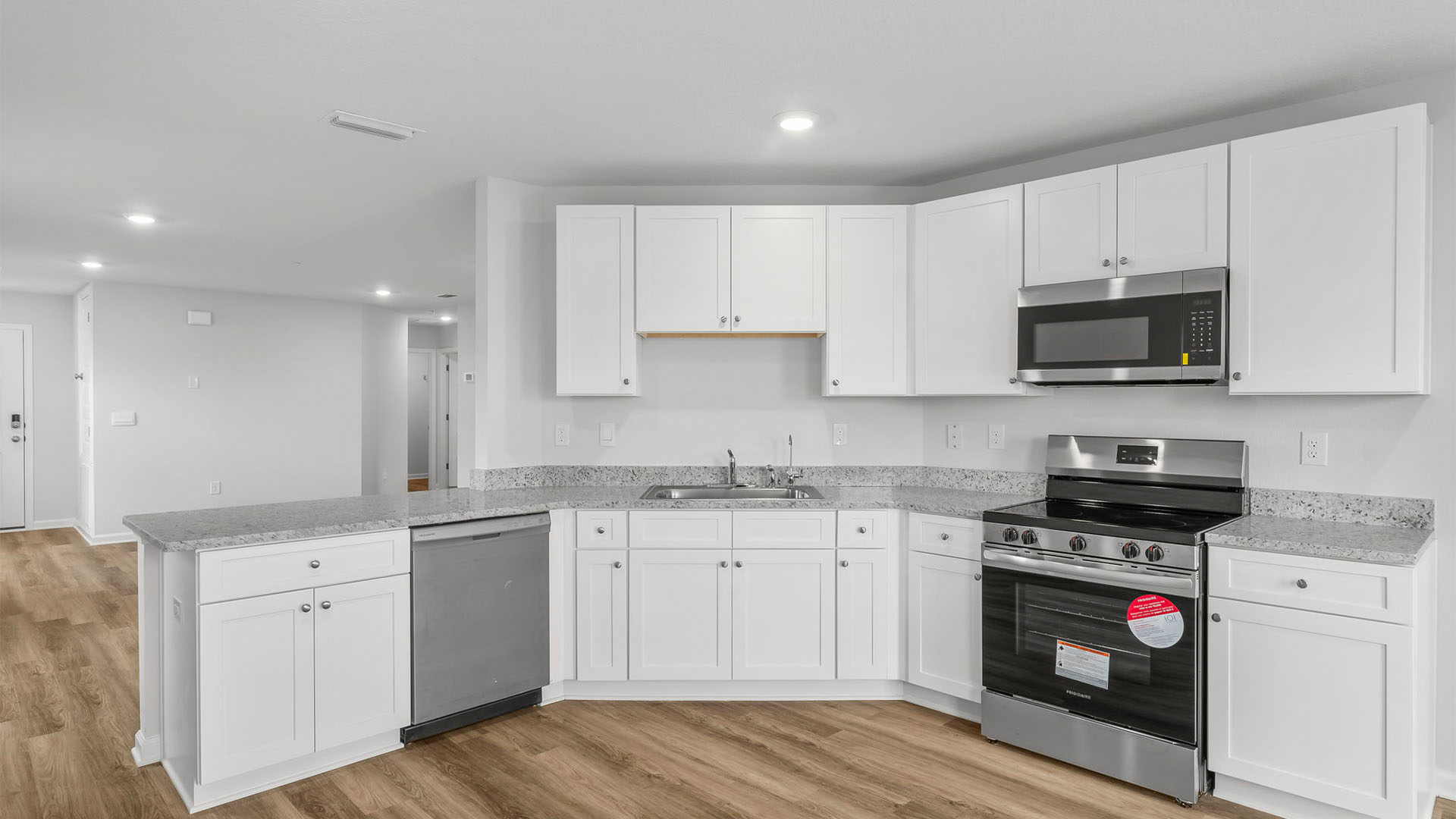 Kitchen with EVP flooring and granite countertops and white cabinets and stainless-steel appliances.