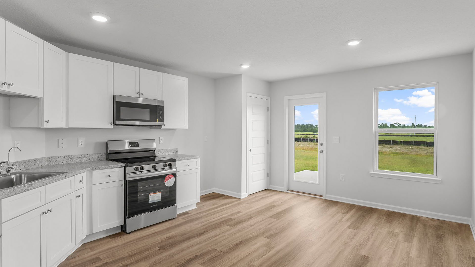 Kitchen with EVP flooring and granite countertops and white cabinets and stainless-steel appliances and back door.