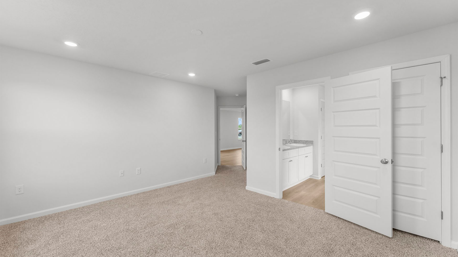 Primary bedroom with closet and bathroom entrance and carpet floors.