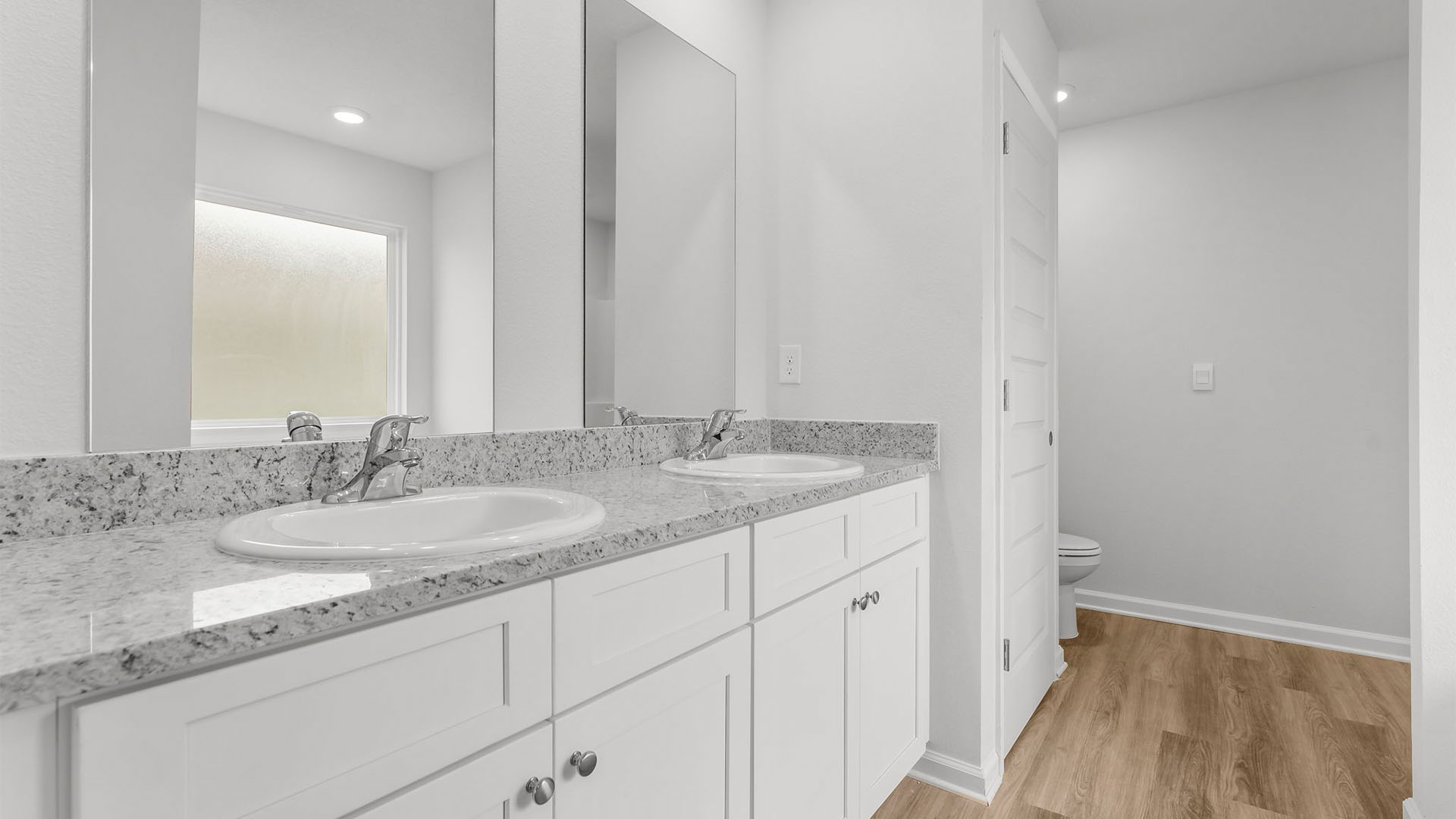 Primary bathroom with double vanity granite countertops and tub and closet.