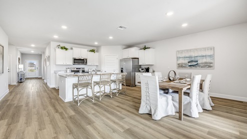 Hodges Bayou Plantation model home kitchen island with white cabinets and stainless-steel appliances and dining room.