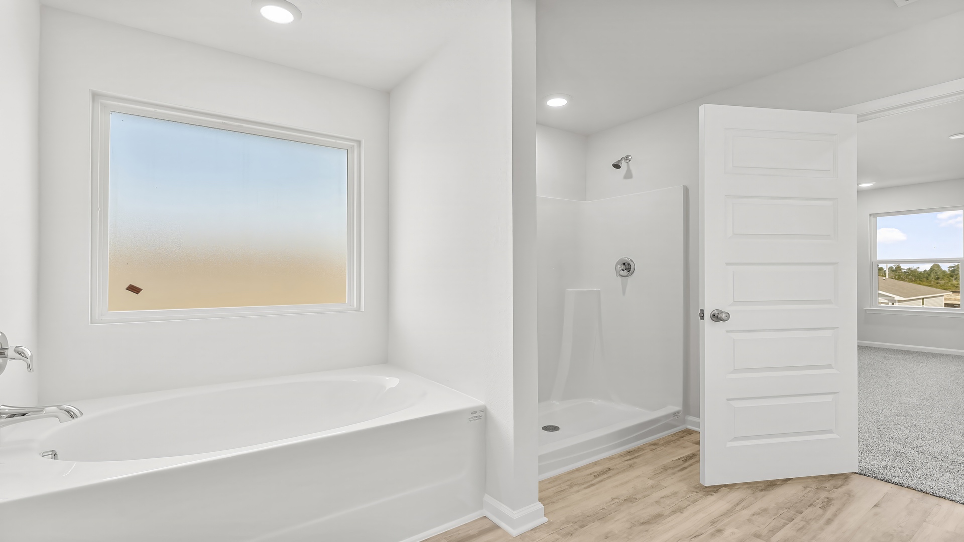 Primary bathroom with separate shower and tub with coated window.