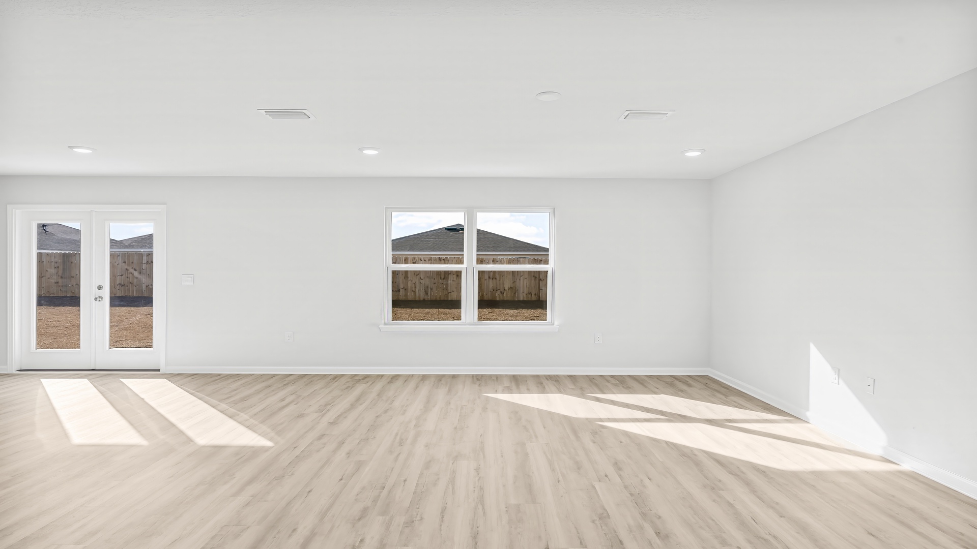 Open living room with EVP flooring and two windows.