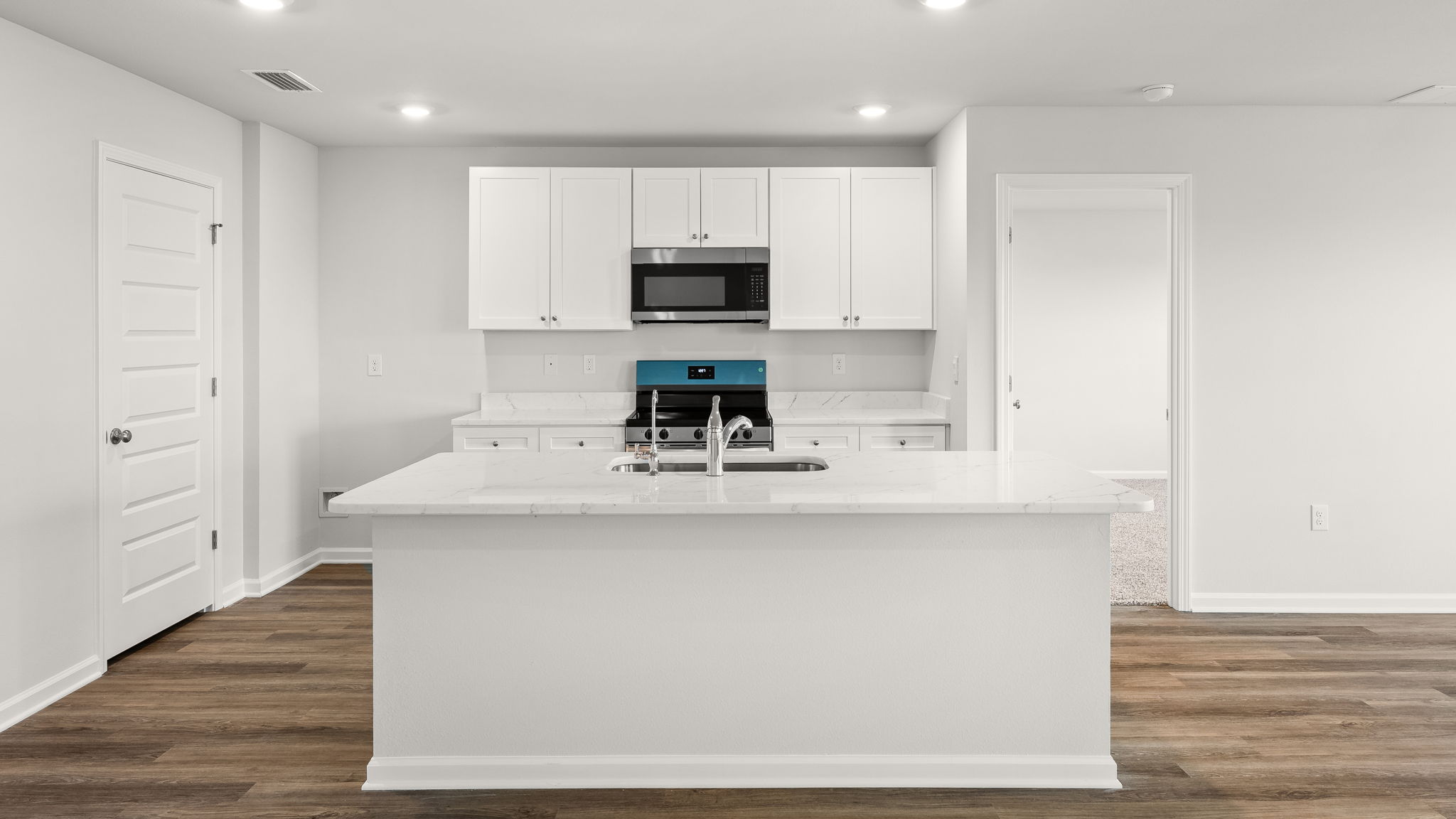 Kitchen with island and quartz countertops with white cabinets and stainless-steel appliances.