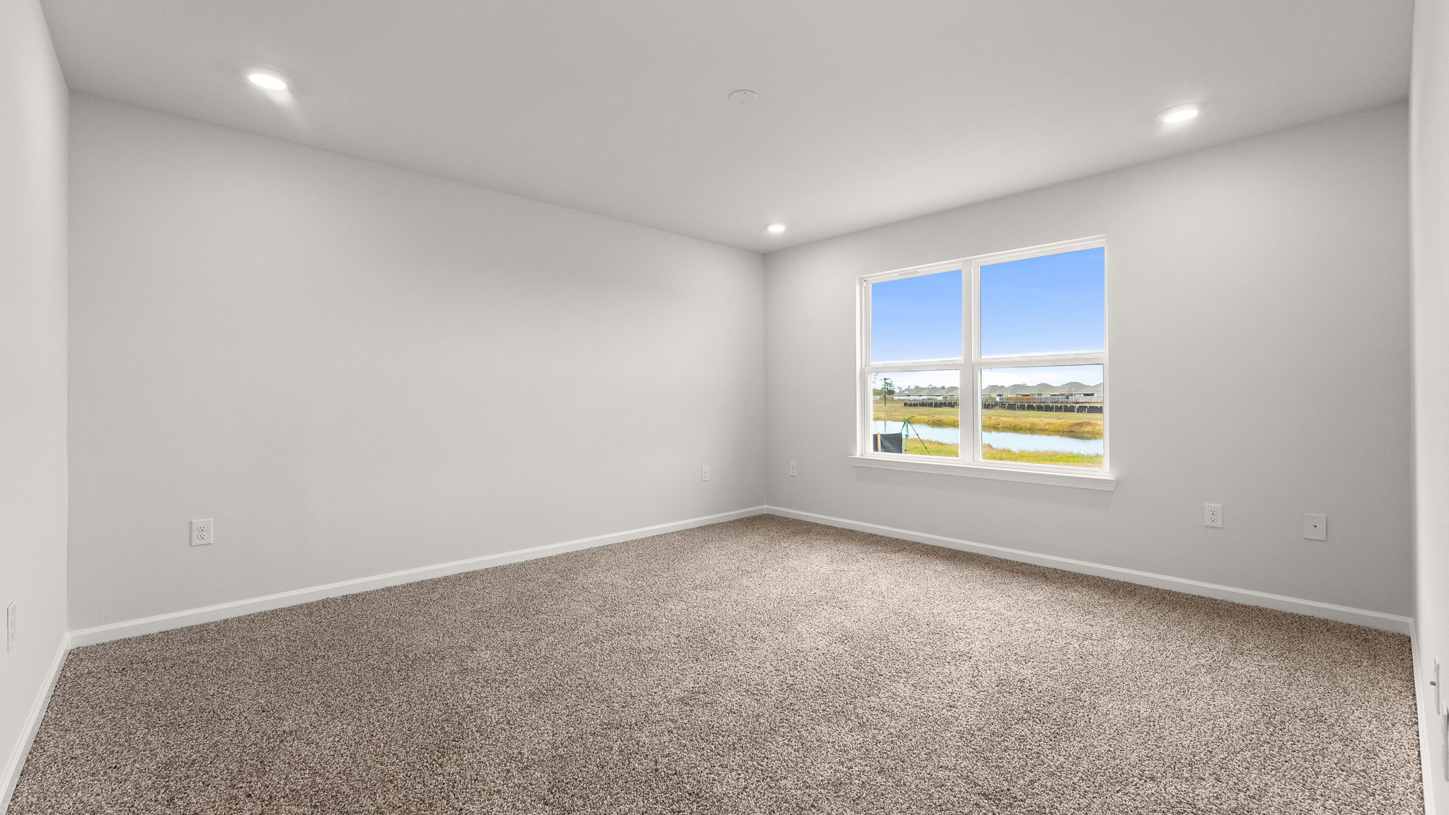 Primary bedroom with carpet flooring and windows.